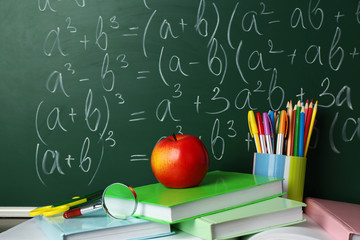 School books on desk near chalkboard