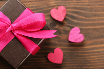 Obraz na płótnie Canvas Gift box and decorative hearts on wooden background