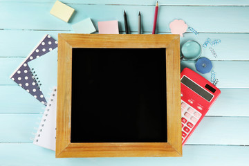 Small school blackboard with stationery on wooden background