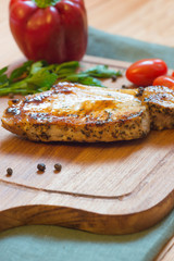 Juicy grilled pork chop (neck cut) on cutting board.