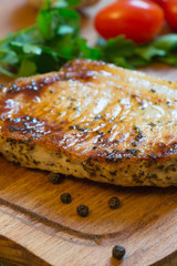 Juicy grilled pork chop (neck cut) on cutting board.