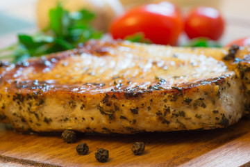 Juicy grilled pork chop (neck cut) on cutting board.