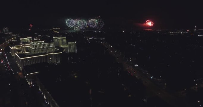 Aerial view of fireworks in the sky over the illuminated building of the Ministry of Defence of Russian Federation, road, river during festival, show or event. Victory day Celebration  in Moscow.