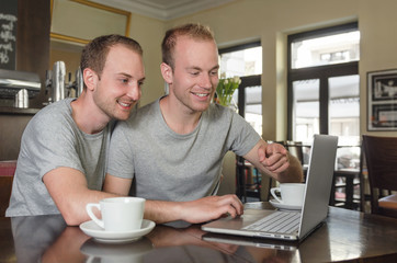  young gays couple using a laptop together at a cafe