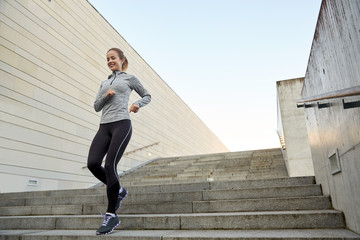 happy sporty woman running downstairs in city