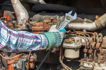 Fototapeta na wymiar Man's hand with adjustable wrench near old diesel engine