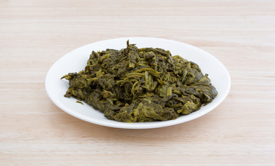Serving of canned spinach on a white plate