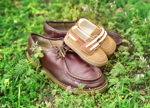 Father's shoes close to child's shoes on grass background