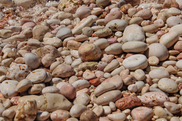 pink pebble beach on the Mediterranean Sea close up.