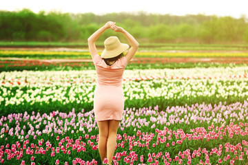 Happy woman on blooming field of tulips