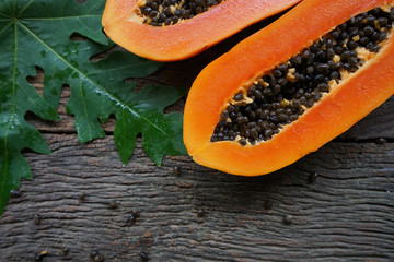 Top view Ripe papaya with green leaf on old wooden background.
