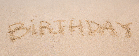 happy birthday written on the sand beach