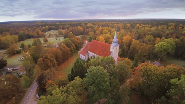 The church surrounded with trees it is the Kaarma church where it is located in the middle of the forest trees and on a hill in Saarema