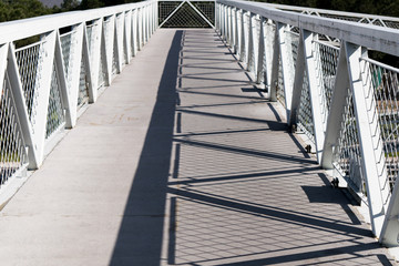 Geometric shadow created by the sunlight on a metal footbridge