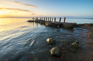 sea landscape, boulders in the water, stone harbor, sunset and colorful sky, slow shutter speed