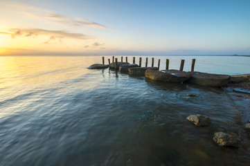 Obraz premium sea landscape, boulders in the water, stone harbor, sunset and colorful sky, slow shutter speed