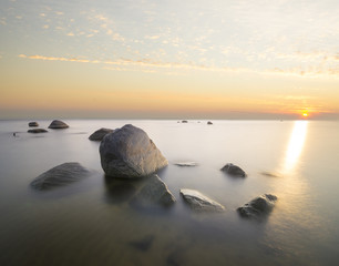 Fototapeta na wymiar sea landscape, boulders in the water,sunset and colorful sky, slow shutter speed