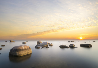 Fototapeta na wymiar sea landscape, boulders in the water,sunset and colorful sky, slow shutter speed