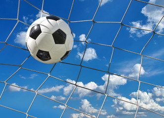 Fototapety  Piłka nożna leci do bramki na tle błękitnego pochmurnego nieba