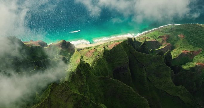 Aerial view flying over jungle mountain peaks revealing tropical coastline, Na Pali coast Kauai