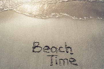Fototapeta premium Beach time hand drawn lettering text on sand. Sunburst