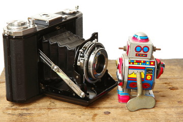 Tin robot toy with Antique Vintage Retro Old Photo Camera compose on wooden plank on white...
