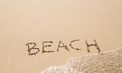word Beach written on the sand