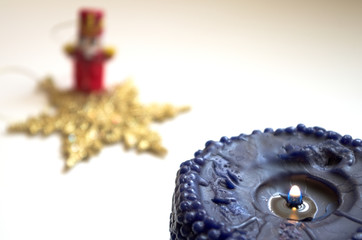 Primo piano di una candela blue accesa con decorazioni natalizie. Sfondo festività, celebrazioni,...
