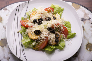 roasted cheese with tomato olives and lettuce topped with chedda