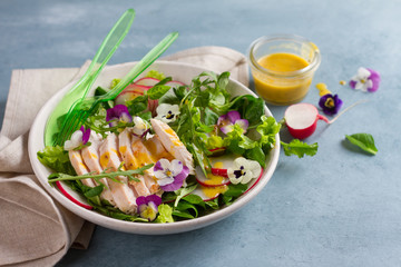 Spring salad with radishes, chicken breast and edible flower
