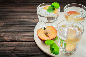 Water with peaches on a wooden background
