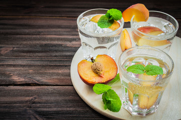 Water with peaches on a wooden background