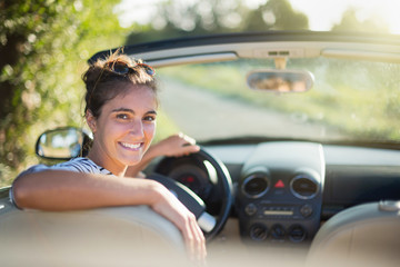 Rear view. A young woman happy to drive her convertible car