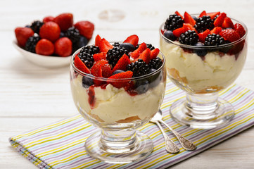 Delisious creamy dessert with biscuits, strawberries, blackberries and blueberries.