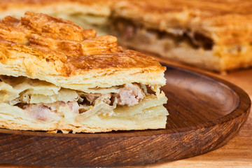 A piece of meat pie on a wooden plate