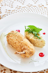 Chicken Kiev fried in breadcrumbs, Parmesan sauce and mashed potatoes with Dijon mustard served on a white plate