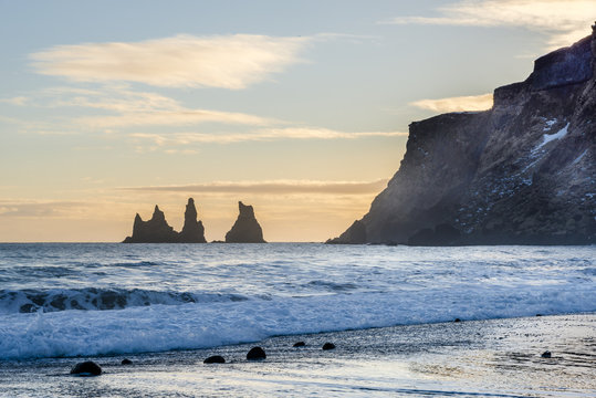 Black sand beach near Reynisdrangar rocks. Golden sunset. Vik, Iceland.