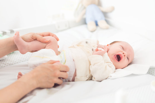 Mother Helping Her Female Newborn Baby Daughter With Hip Excercise