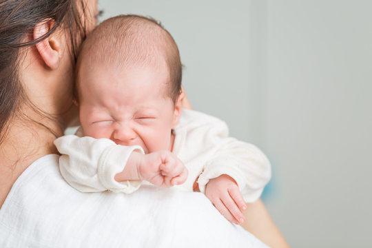 Newborn baby screaming in pain with colic on mother's shoulders