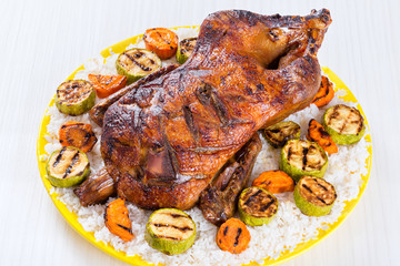 Roasted Whole Duck in honey mustard soy glaze on a yellow platter white background, close-up