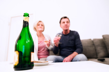 Senior couple sitting in living room , drinking champagne