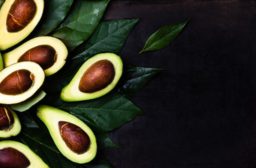Fresh avocado with leaves on black background