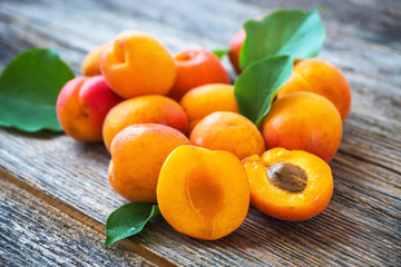 Organic apricots with leaves on wooden background