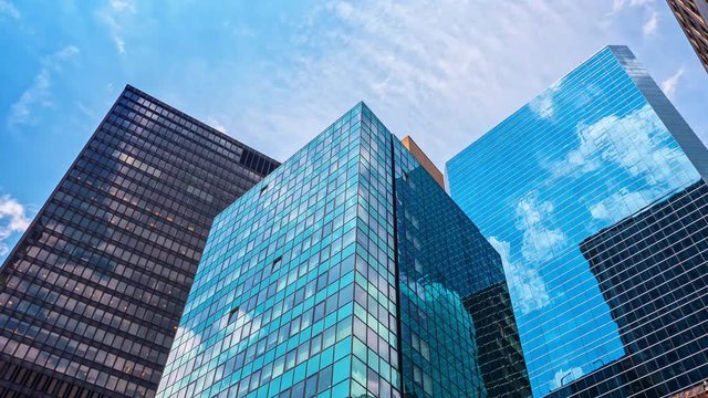 Glass skyscrapers blue sky reflection mirror facades corporate buildings Manhattan New York City NYC timelapse