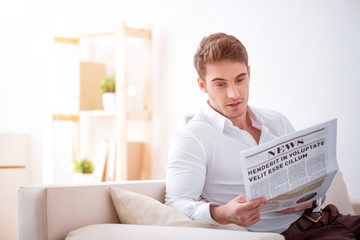 Fototapeta na wymiar Pleasant delighted man reading newspaper 