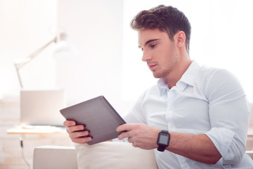 Pleasant brutal man using tablet 