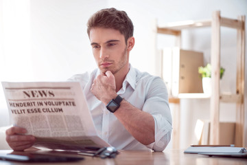 Brutal handsome man reading newspaper 