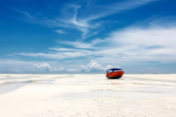Red boat on the beach of Zanzibar on the blue sky background.