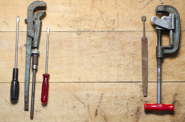 Clamp, screwdriver, and wrench on grunge wooden background , copy space