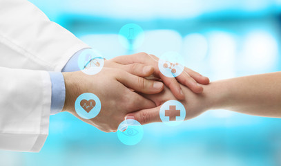 Male doctor holding patient's hand, on blurred background